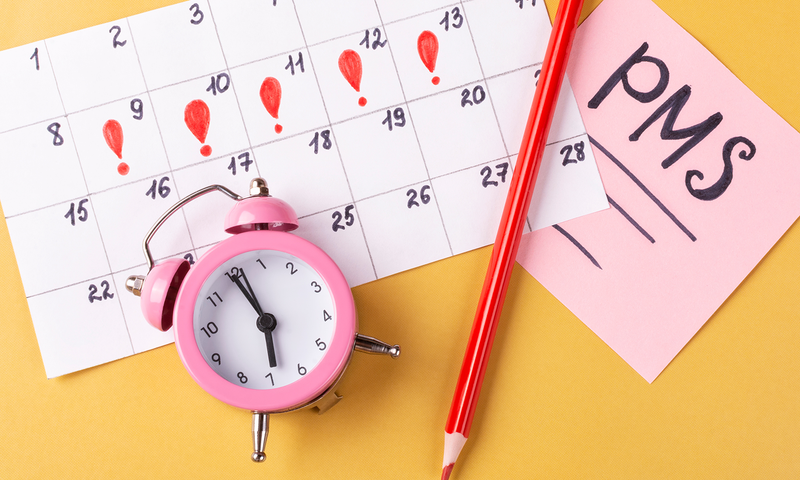 Bild mit einem Menstruation-Kalender, Wecker und Stift