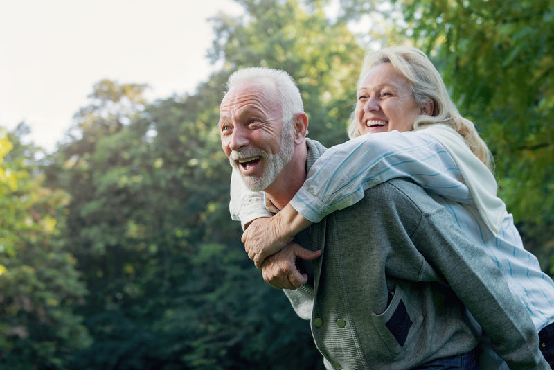 Longevity: Ältere Frau umarmt älteren Mann von hinten 