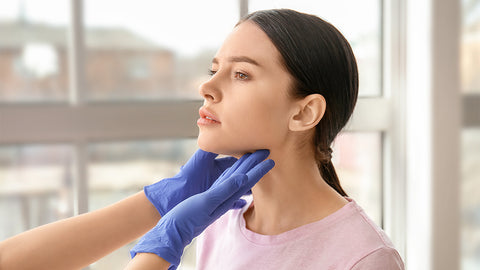 Arzt tastet Schilddrüse einer Frau ab