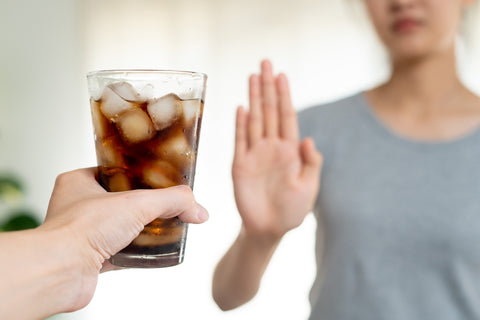 Frau lehnt ein Glas Cola ab