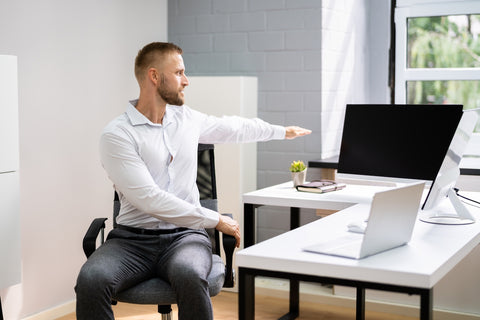 Mann macht eine Dehnübung im Büro