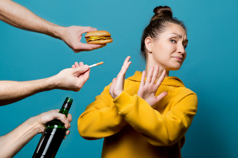 Frau sagt Nein zu einem burger, einer Zigarette und einer Flasche Alkohol