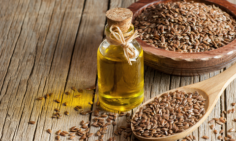 Omega-3-Fettsäuren: Leinsamen auf einem Löffel und eine Flasche mit Leinöl