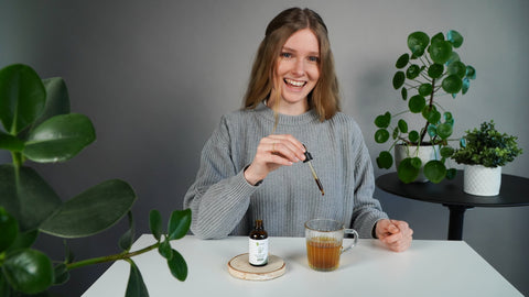 Bitterstoffe Wirkung: Anwendung der VitaMoment Bitterstofftropfen - Frau tropft Bitterstoffe mit Pipette in Tee