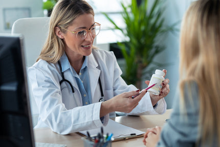 Ärztin erklärt Patientin die Angaben auf einer Dose eines Nahrungsergänzungsmittels