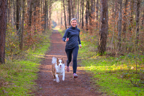 Erfahrung Meno-Balance-Kur: Frau joggt mit ihrem Hund durch den Wald