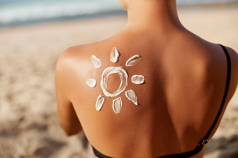 Falten vorbeugen: Sonnencreme auf dem Rücken einer Frau