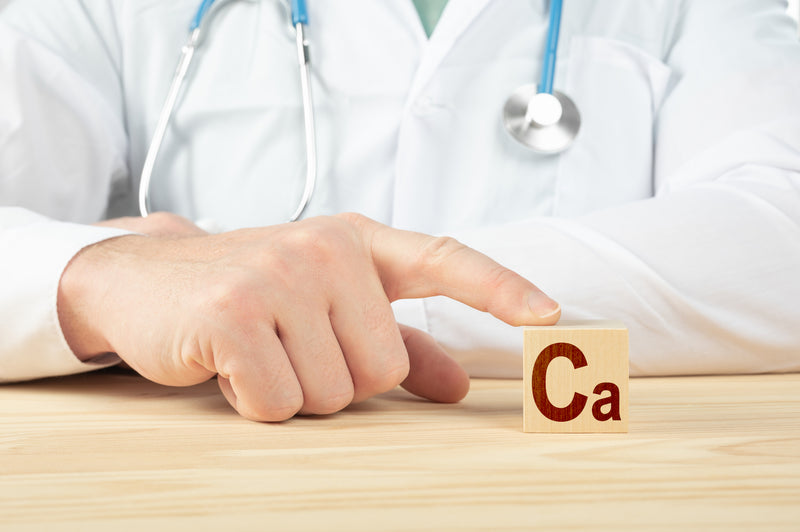 Arzt hält Finger auf Holzklotz mit der Aufschrift Ca
