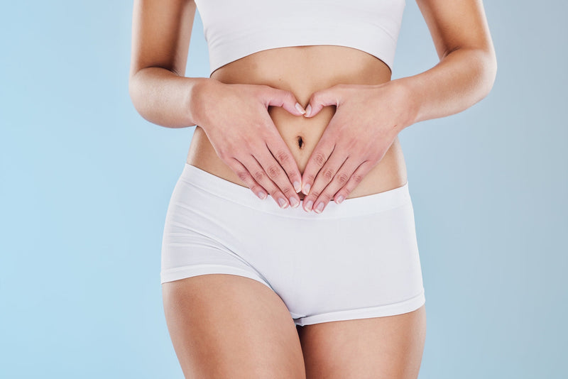 Person legt Hände auf ihren Bauch und bildet mit Fingern ein Herz