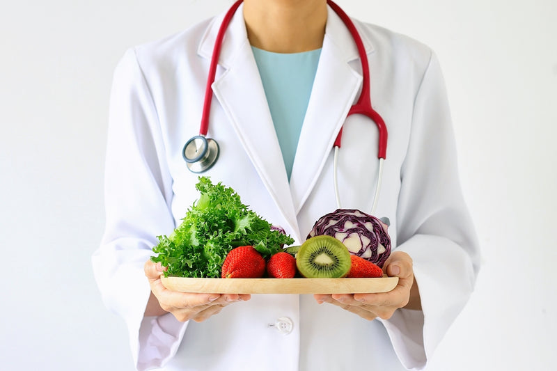 Arzt hält Tablett mit Obst und Gemüse in der Hand