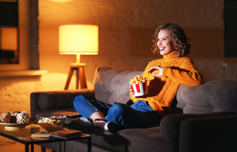 Frau sitzt mit Popcorn vor dem Fernseher