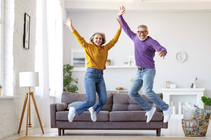 Mann und Frau springen freudig vom Sofa