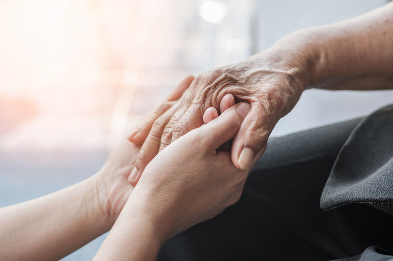 Person hält Hand einer anderen Person zwischen ihren Händen