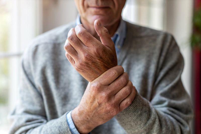 Älterer Mann umfasst eine Hand mit der anderen