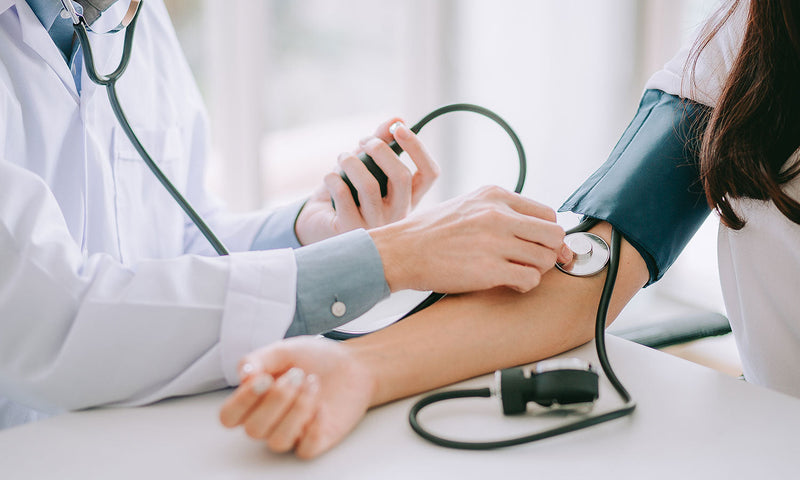 Arzt misst Blutdruck bei Patient