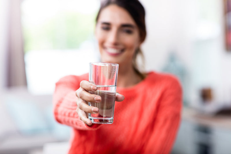 Frau hält Glas mit Wasser in die Kamera