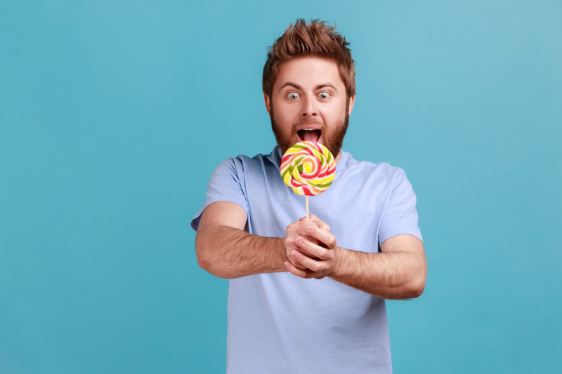 Mann hält einen großen bunten Lolli in den Händen