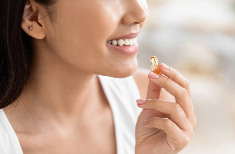 Omega-3-Erfahrung: Frau nimmt lächelnd eine Kapsel Omega 3 ein