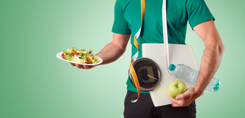 Sportlicher Mann hält Teller Salat Apfel und Flasche Wasser