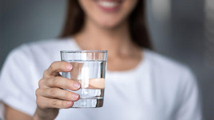 Frau zeigt ein Glas Wasser