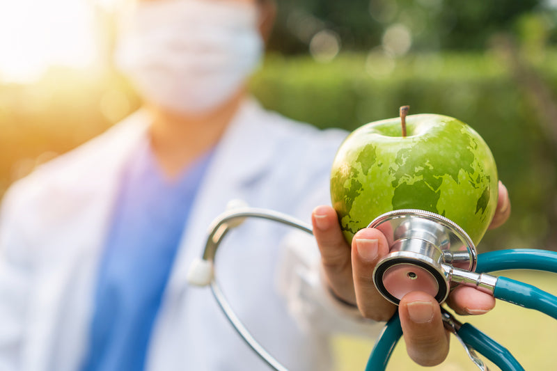 Arzt hält Apfel und Stethoskop