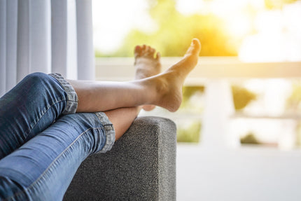 Schwere Beine Hausmittel: Frau liegt auf dem Sofa und lagert die Beine hoch