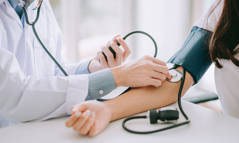 Arzt misst bei Patientin den Blutdruck