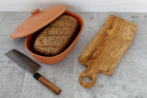 Brot in einem Kasten, daneben Messer und Schneidebrett