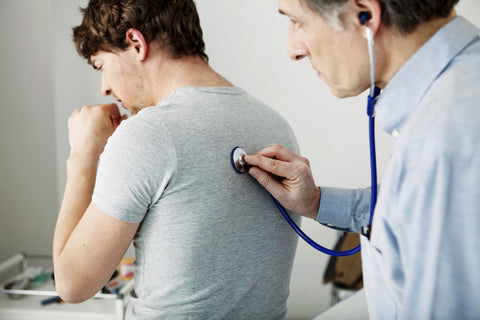 Arzt hört Rücken des Patienten mit Stethoskop ab