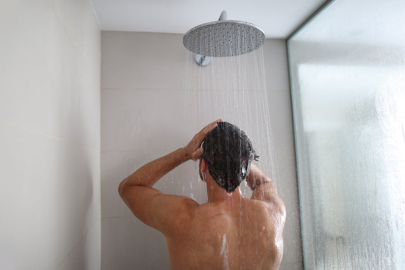 Mann steht unter der Dusche