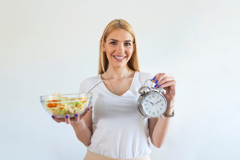 Frau hält Schüssel mit Salat und einen Wecker in den Händen