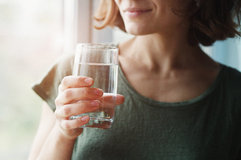 Eine Frau trinkt aus einem Glas Wasser