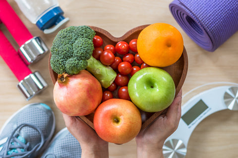 Schale mit Obst und Gemüse, Waage, Hanteln, Sportmatte und Sportschuhe