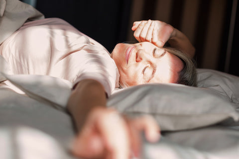 Eine Frau wacht grinsend und ausgeruht im Bett auf
