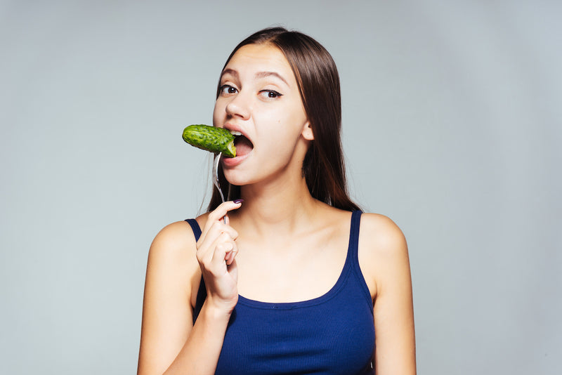 Frau isst eine Gewürzgurke