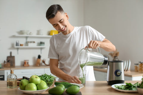Mann macht sich Smoothie aus grünem Gemüse