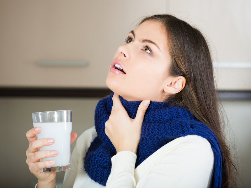 Frau gurgelt mit einem Glas Salzwasser