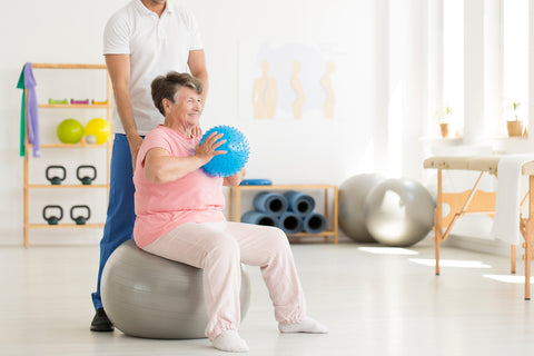 Die richtige Ernährung bei Arthrose: Ältere Frau macht Gymnastikübungen auf einem Gummiball