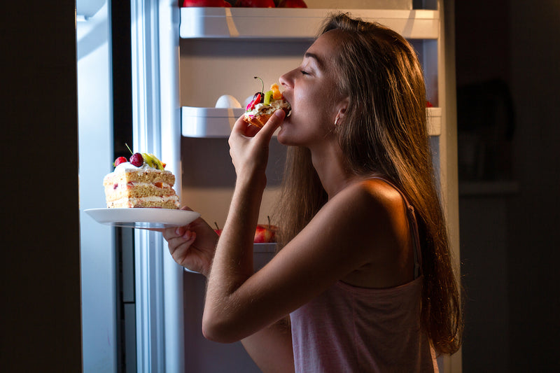 Frau isst Torte aus dem Kühlschrank