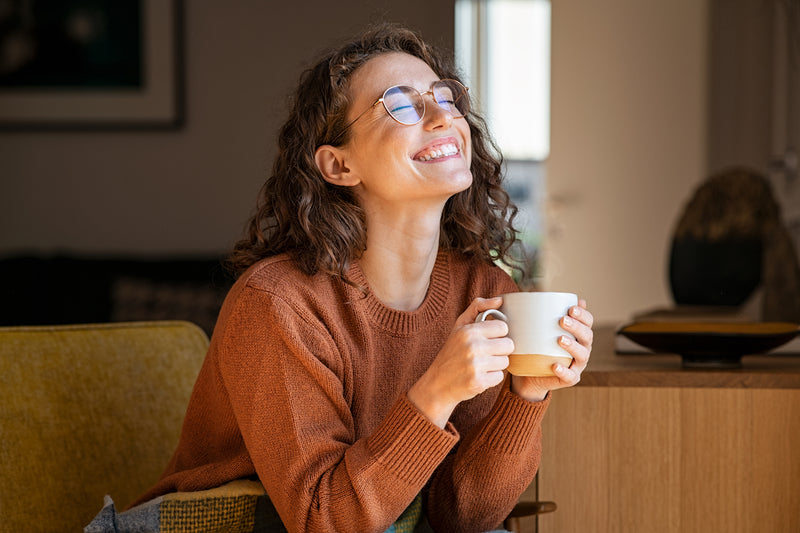 Frau hält Kaffeetasse in der Hand und lacht