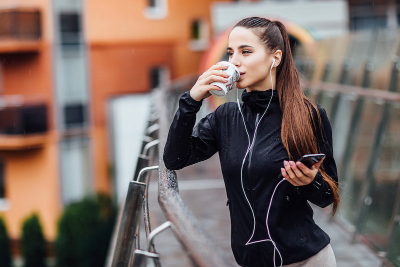 Frau in Sportsachen trinkt Kaffee