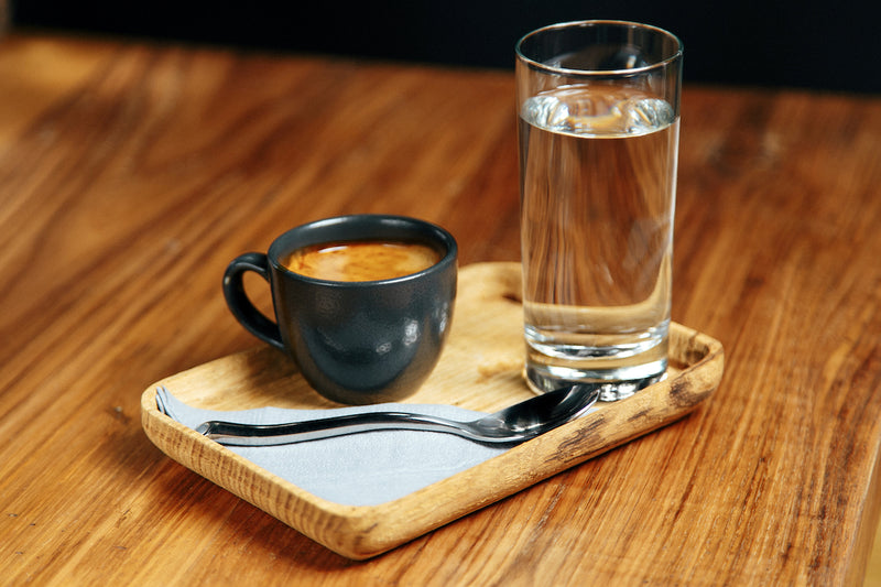 Kaffeetasse und Glas Wasser auf einem Tablet