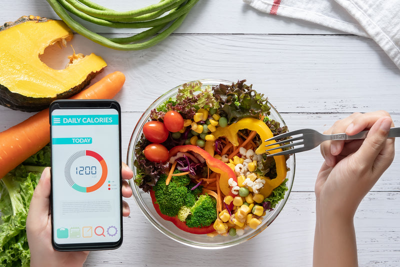 Eine Schüssel mit Essen und eine App auf dem Handy zum Kalorien tracken