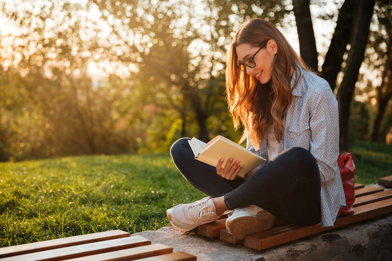 Gesunde Gewohnheiten: Frau sitzt im Garten und liest ein Buch