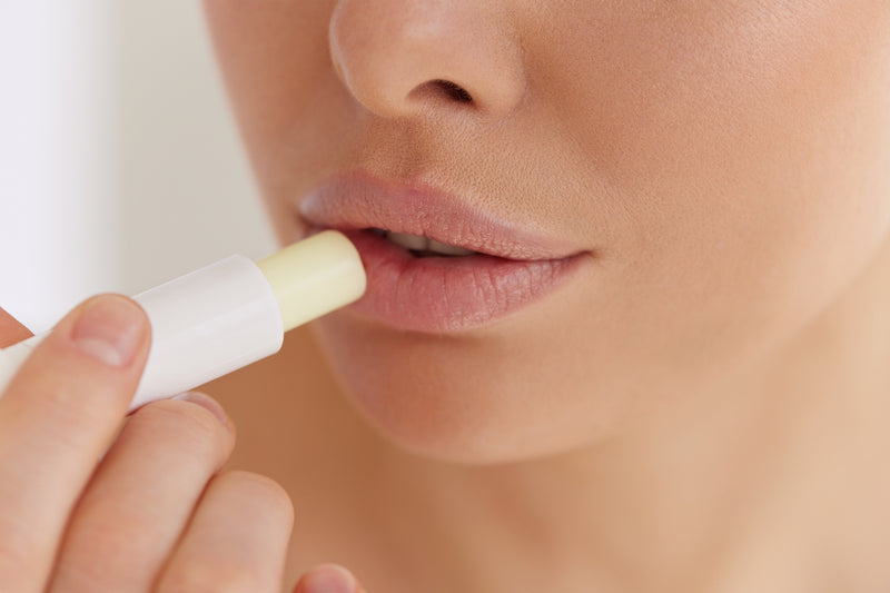 Frau benutzt Lippenpflegestift