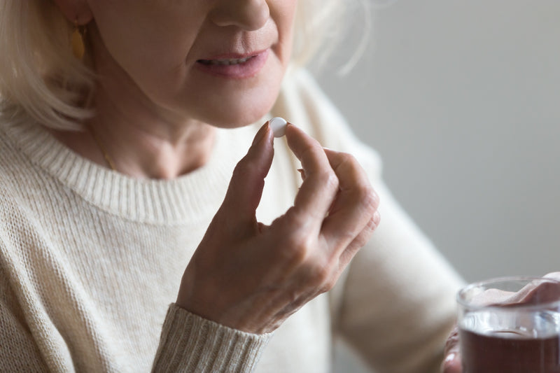 Eine Frau nimmt ein Medikament oral mit einem Schluck Wasser ein