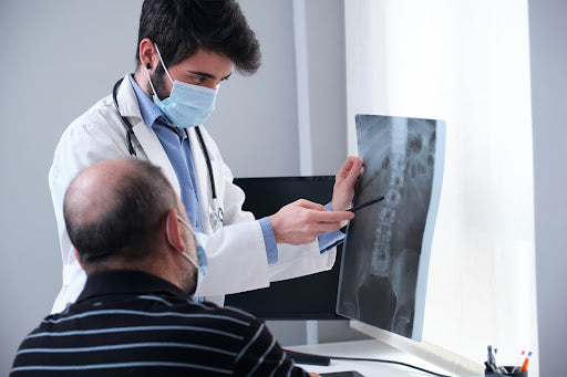 Osteochondrose Symptome, Ursachen, Therapie: Arzt zeigt Patient Aufnahme der Wirbelsäule