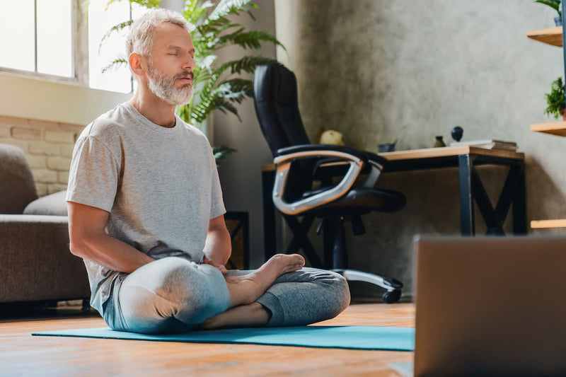Immunsystem stärken: Mann sitzt auf einer Yogamatte und meditiert
