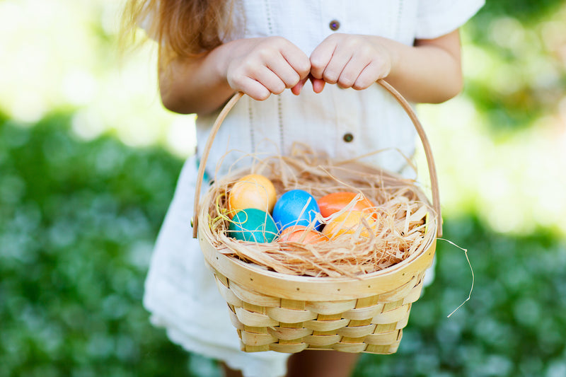 Gesund naschen Ostern: Kind hält Korb mit bunten Ostereiern