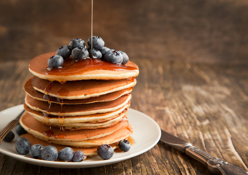 Protein Pancake Rezepte: Teller mit Pancakes, Blaubeeren und Honig
